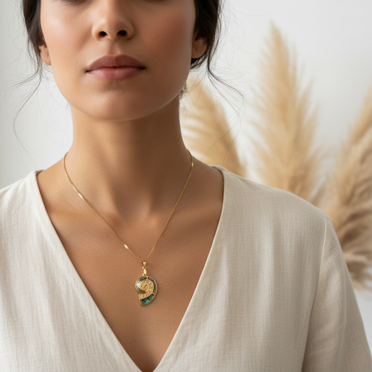 Collier chaîne dorée et pendentif coquillage nacré porté au centre du décolleté
