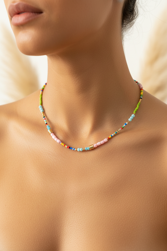 Collier bohème à perles multicolores sur le cou, tons bleu, rose et vert, chaîne dorée.