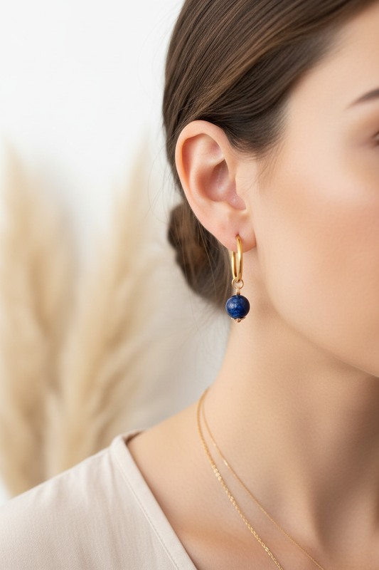 Boucles d’oreilles créoles dorées épaisses avec perle bleue marine sur l’oreille