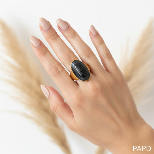 Bague dorée ajustable résine noire ovale portée main fond blanc pampa — bijou artisanal PAPD fait main France