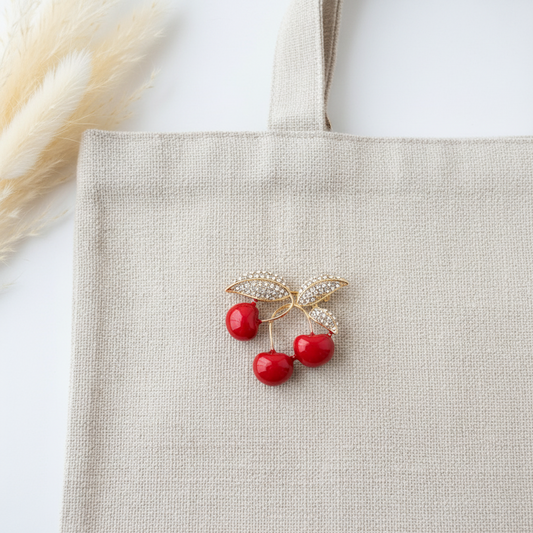 Broche cerises rouges, feuilles dorées serties de strass sur tote beige