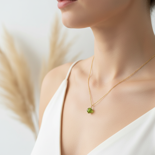 Collier fin doré avec perle verte ronde, porté au cou