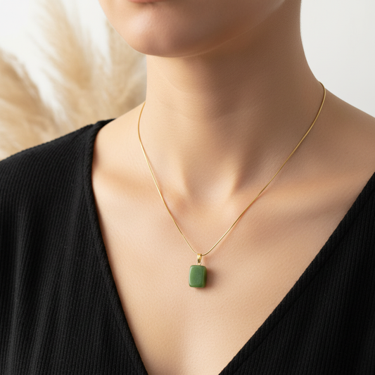 Collier à chaîne fine dorée et pendentif carré en jade vert, porté au cou