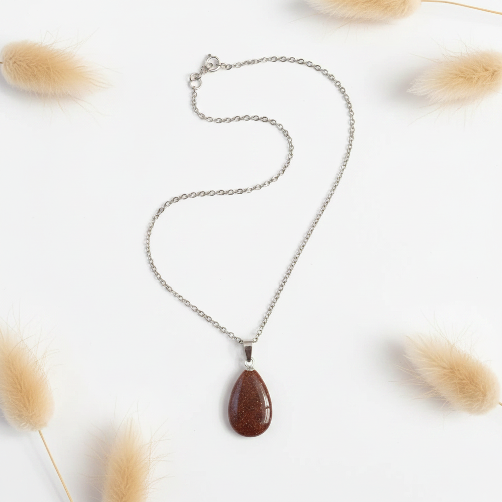 Collier en chaîne argentée avec pendentif goutte brun, posé à plat