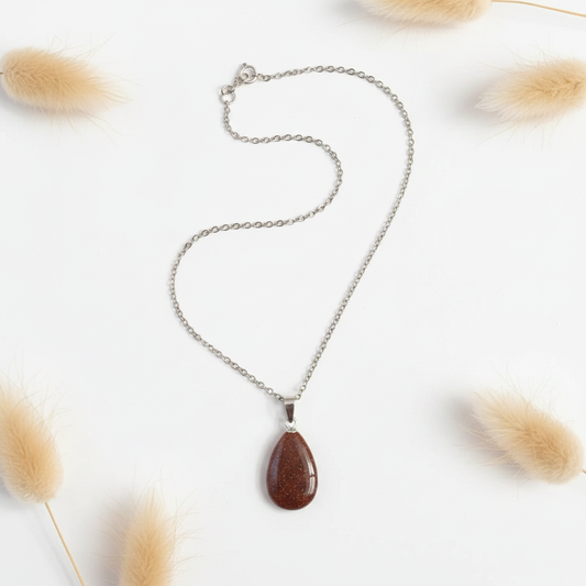 Collier en chaîne argentée avec pendentif goutte brun, posé à plat