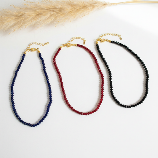 Lot de trois colliers perles facettées bleue, rouge et noire, fermoir doré.