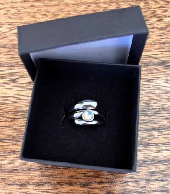 Bague ajustable en argent inox et opale blanche ronde, dans écrin ouvert