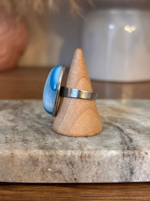 Bague ajustable argentée avec cabochon ovale bleu aventurine et anneau fin métallique.