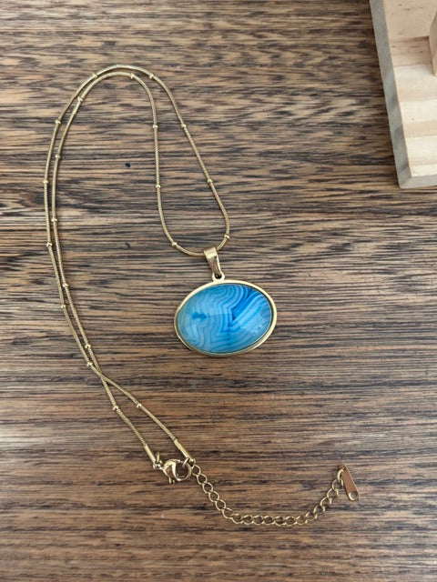 Collier chaîne dorée avec pendentif ovale cabochon bleu et fermoir avec chaînette