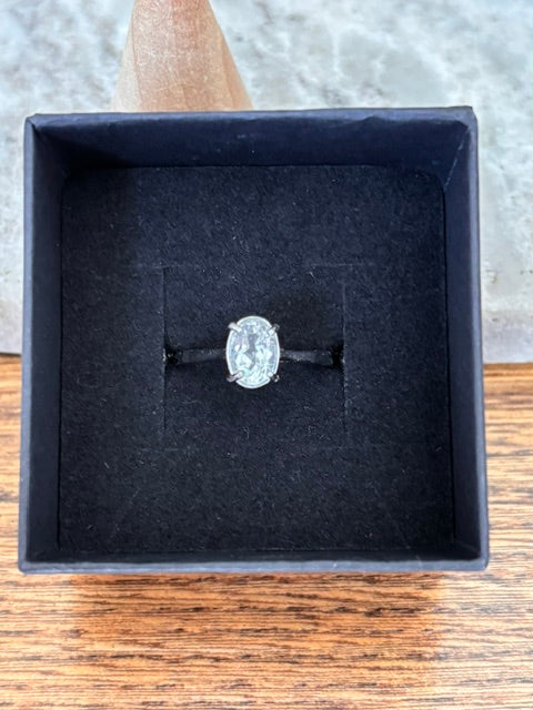 Bague solitaire en argent 925 rhodié avec topaze blanche, vue de dessus sur écrin noir