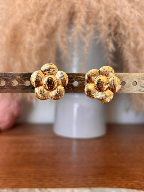 Puces d’oreilles en forme de fleur dorée, détail des pétales texturés