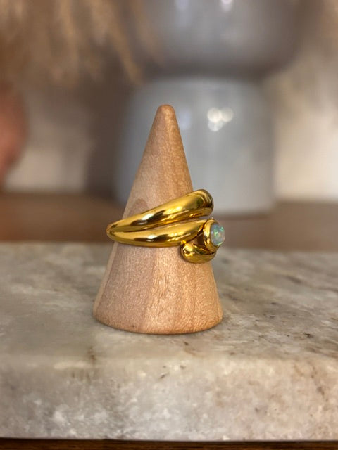 Bague dorée en acier inoxydable avec cabochon d’opale blanche sur présentoir conique