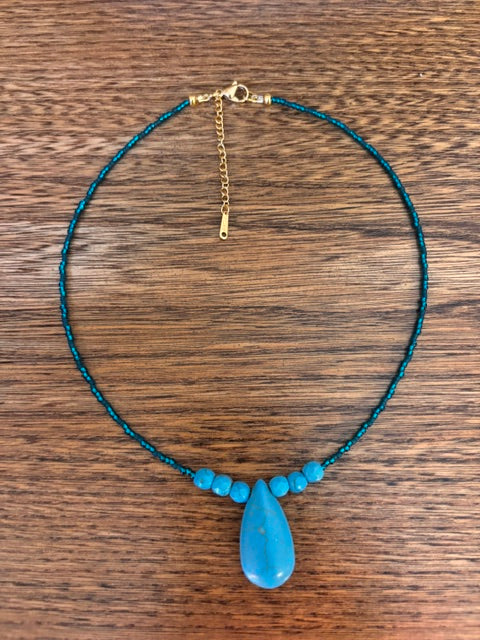 Collier en perles turquoise avec pendentif goutte, petite chaînette dorée en fermoir.