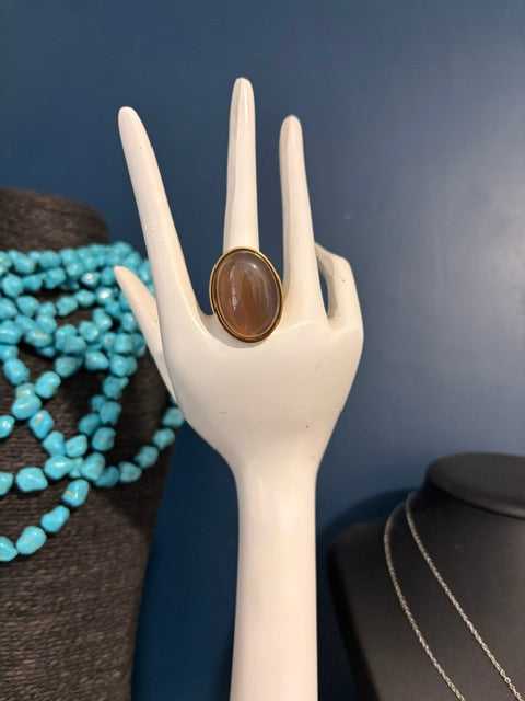 Bague dorée ajustable en Pierre de Lune grise présentée sur une main décorative blanche