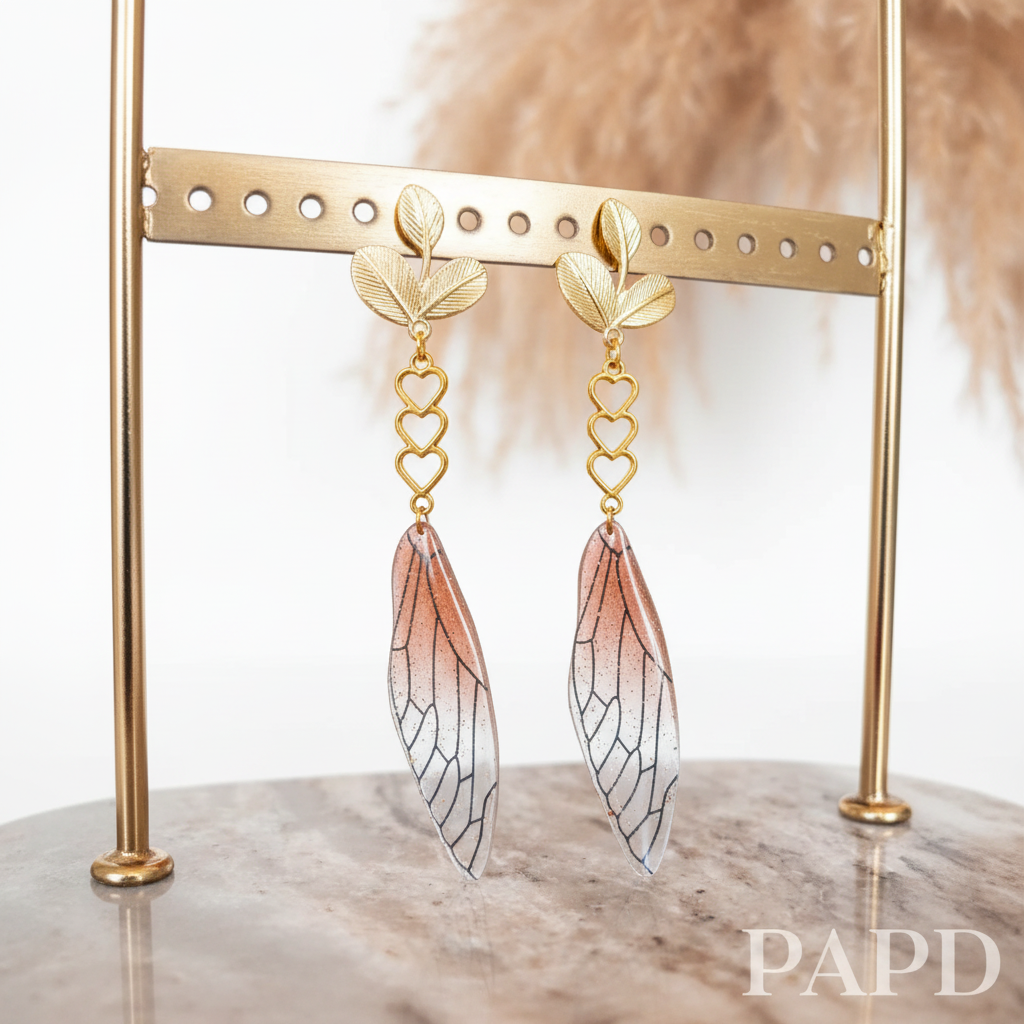 Boucles pendantes dorées: cœurs en triple, ailes veinées brun-ocre, feuillages.
