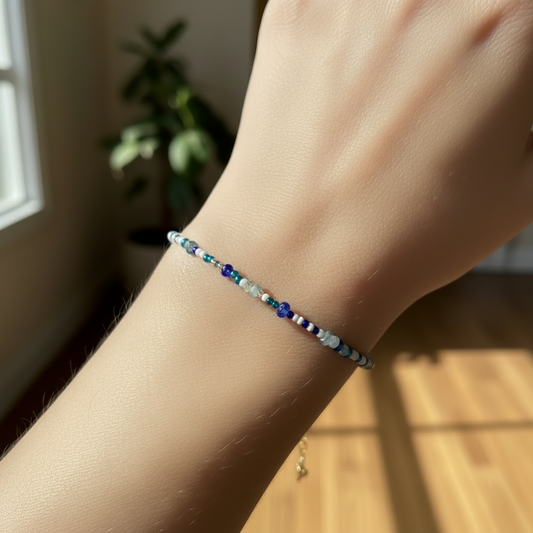 Bracelet à perles bleu clair et bleu cobalt sur poignet, fermoir doré visible.