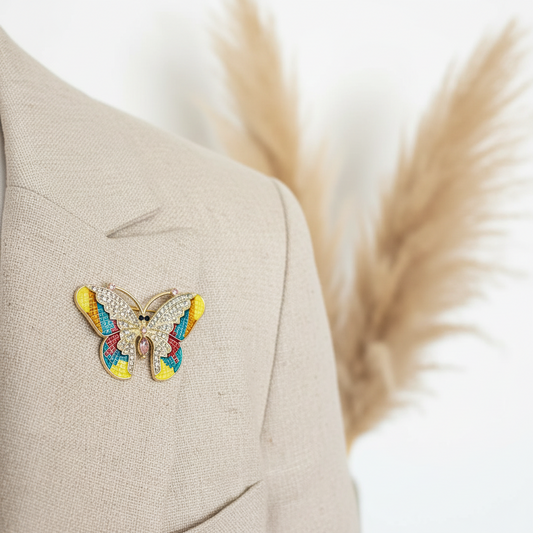 Broche papillon dorée multicolore à strass, sur veste beige
