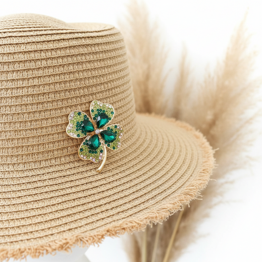 Broche trèfle à quatre feuilles dorée en strass verts sur chapeau de paille