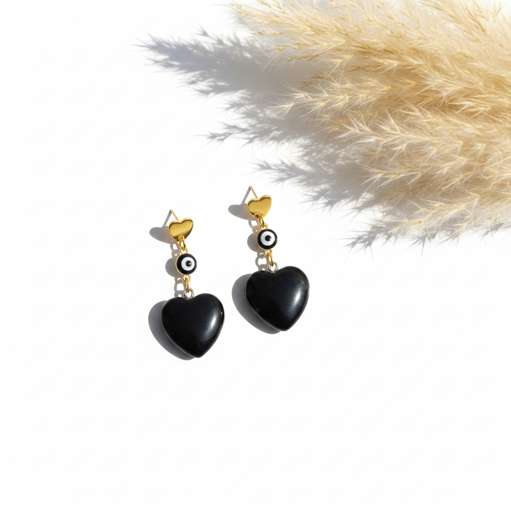 Boucles d’oreilles pendantes cœur noir, monture dorée, petit motif œil.
