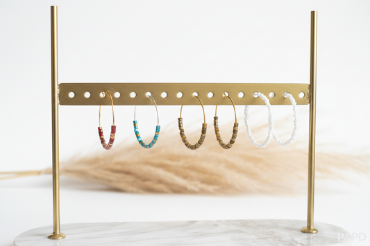 Série de créoles à perles multicolores sur présentoir : vert, rouge, brun et blanc.
