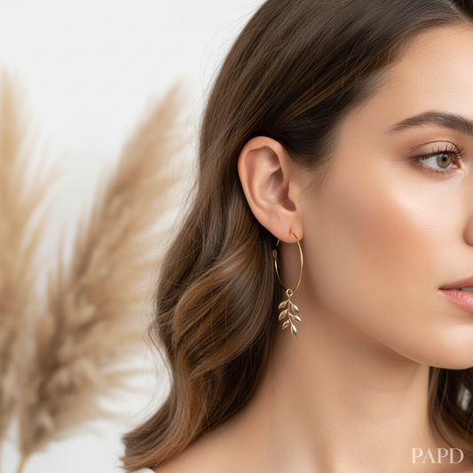 Boucles créoles dorées portées, anneau fin avec breloque feuille en détail