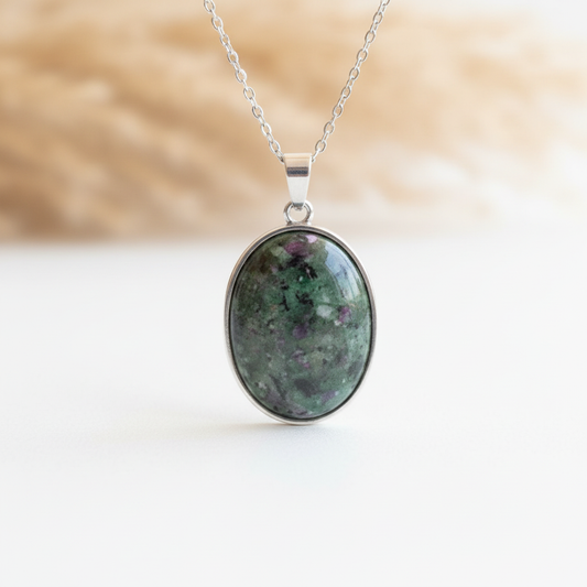 Gros plan d’un pendentif ovale en Zoïsite naturelle aux reflets verts et rosés, monture argentée 18 x 25 mm et chaîne 316L argentée