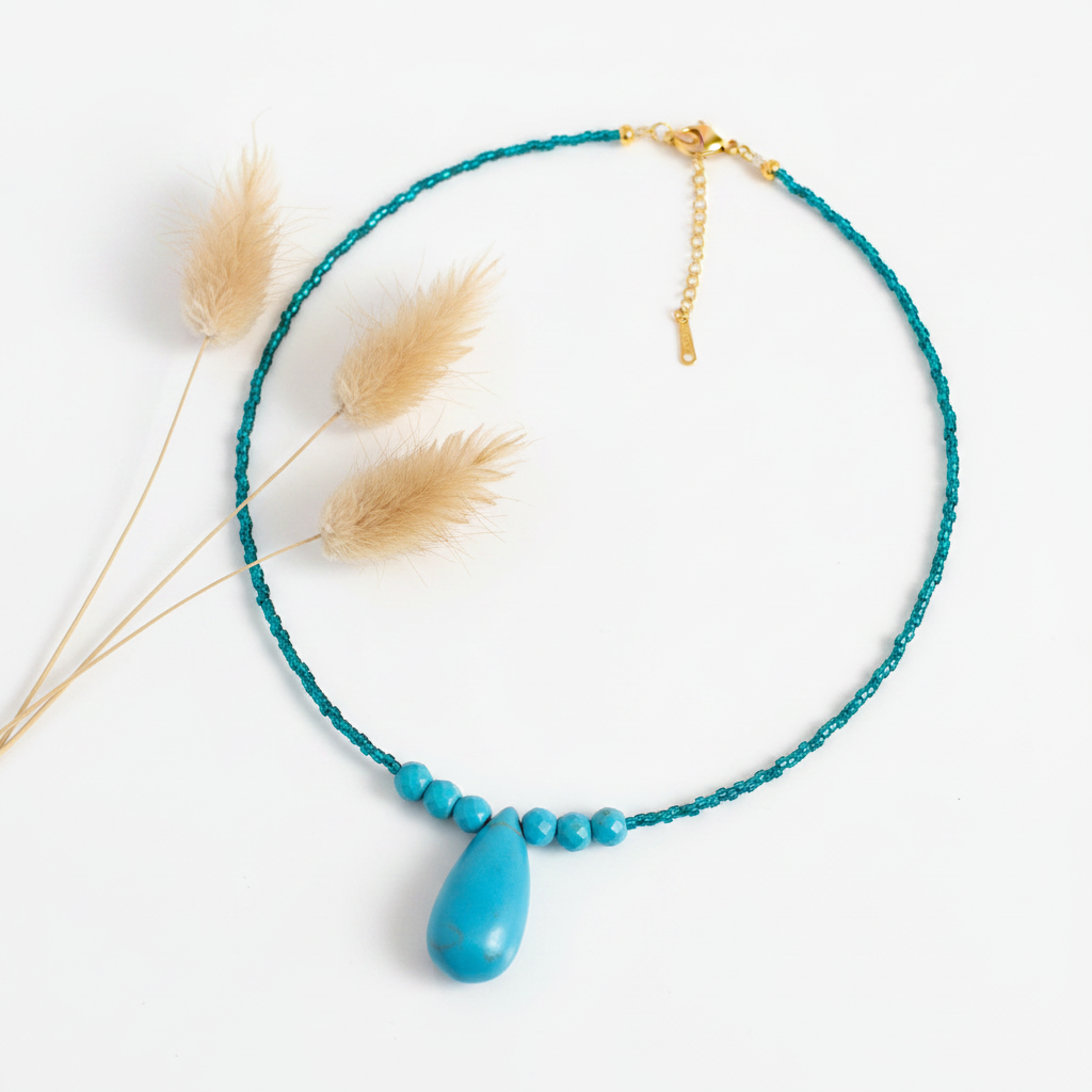 Collier en perles turquoise et pendentif goutte, chaîne dorée avec détail central.