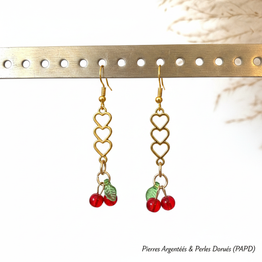 Boucles d’oreilles pendantes dorées : trois cœurs et cerises rouges, à crochets.