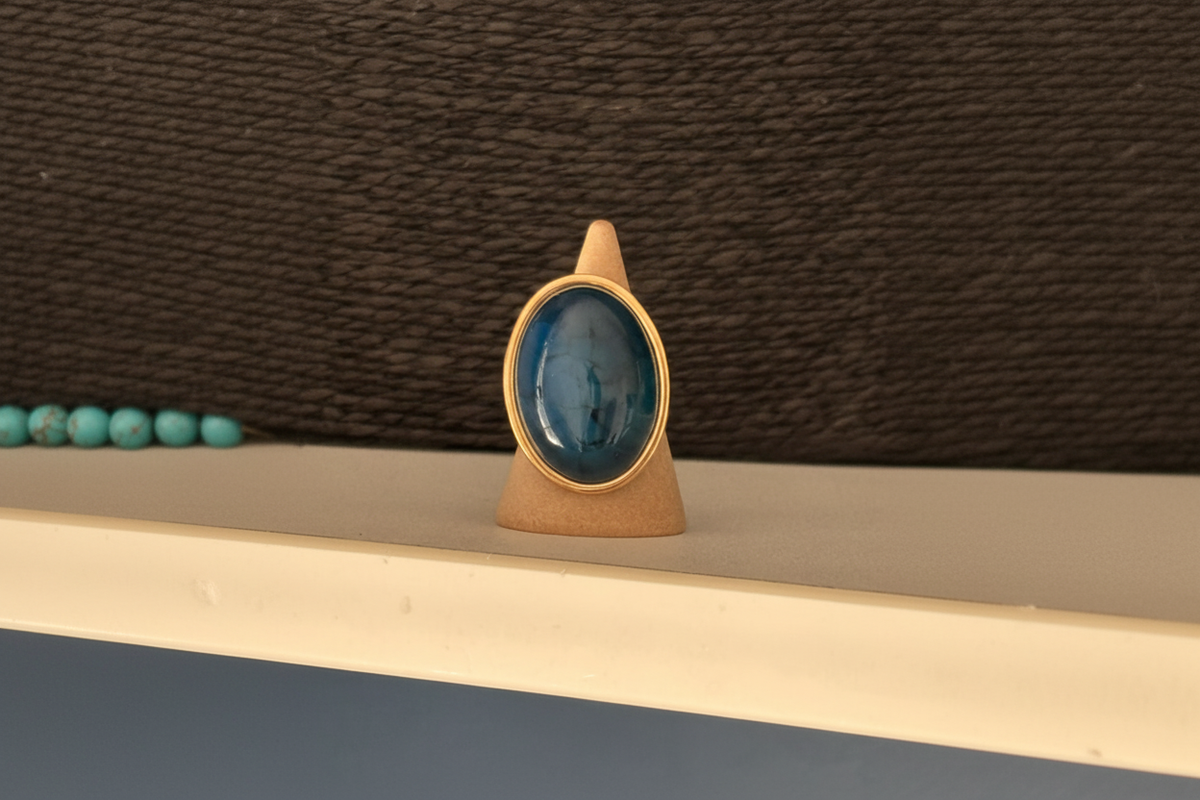 Bague dorée ajustable en Agate Veine de Dragon bleue présentée sur une main décorative blanche