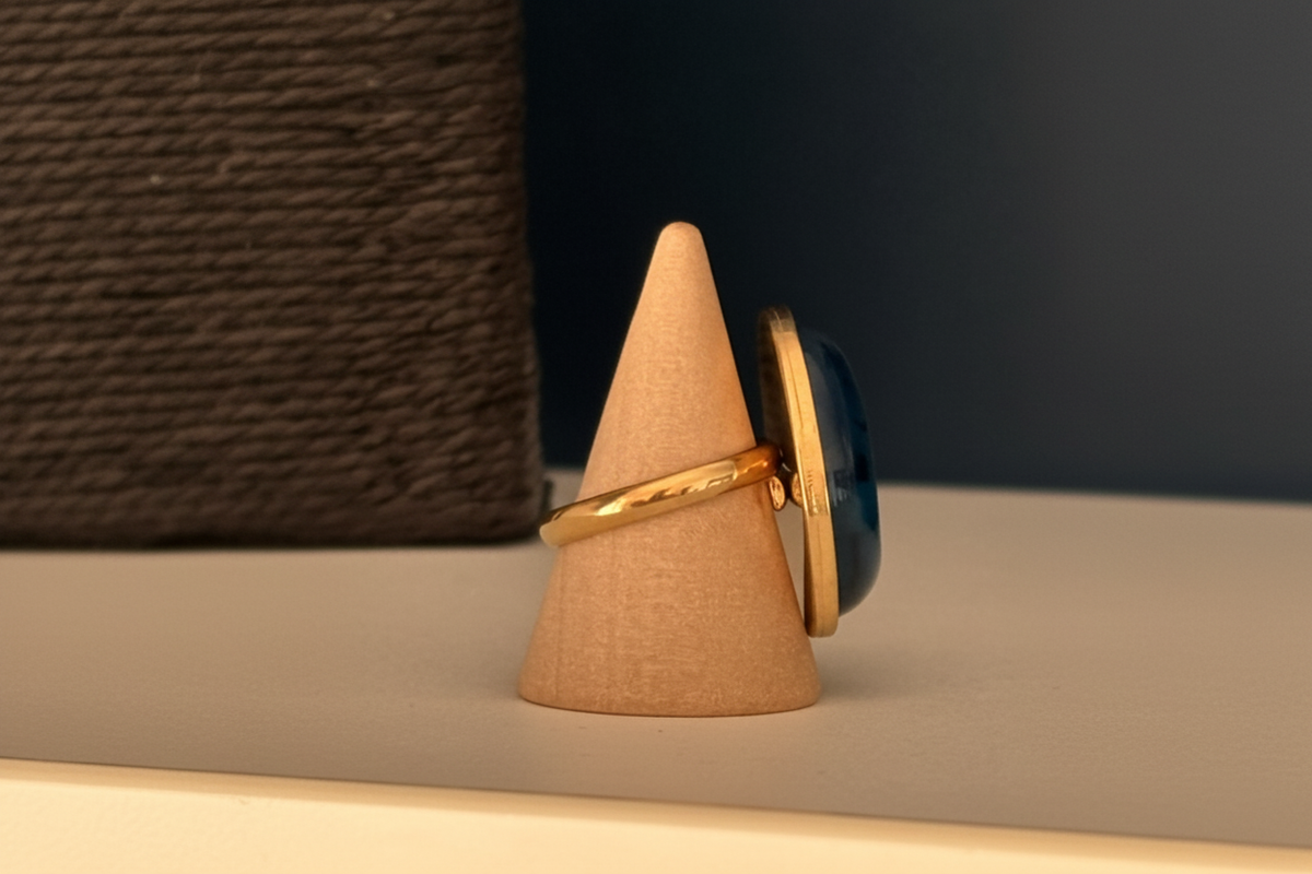 Gros plan du cabochon ovale bleu à veines noires de la bague dorée ajustable