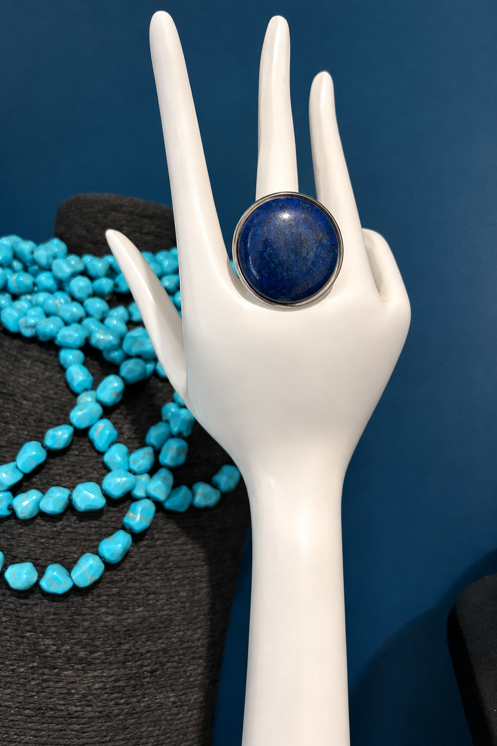 Bague en lapis-lazuli, cabochon rond bombé bleu foncé de 25 mm sur monture argentée, présentée sur une main factice
